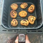 Air fryer basket with freshly baked chocolate chip cookies, showing a golden-brown texture, perfect for an easy dessert using the air fryer method.
