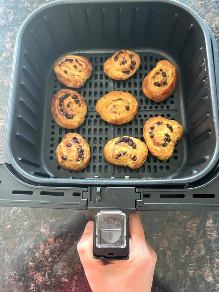 Air fryer basket with freshly baked chocolate chip cookies, showing a golden-brown texture, perfect for an easy dessert using the air fryer method.