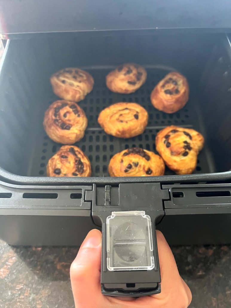 Hand holding the air fryer basket with perfectly baked Trader Joe’s Mini Croissants inside, showing their golden, crispy texture after air frying.