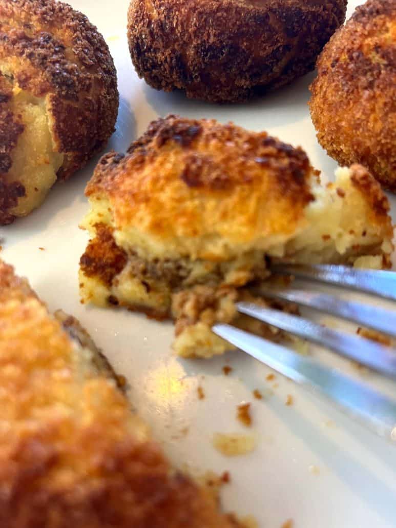 Close-up of a fork cutting into a crispy Trader Joe’s Papas Rellenas, showing the beef filling inside.