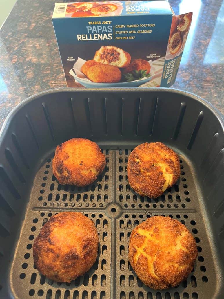 Cooked Trader Joe’s Papas Rellenas in an air fryer basket with the packaging box in the background.