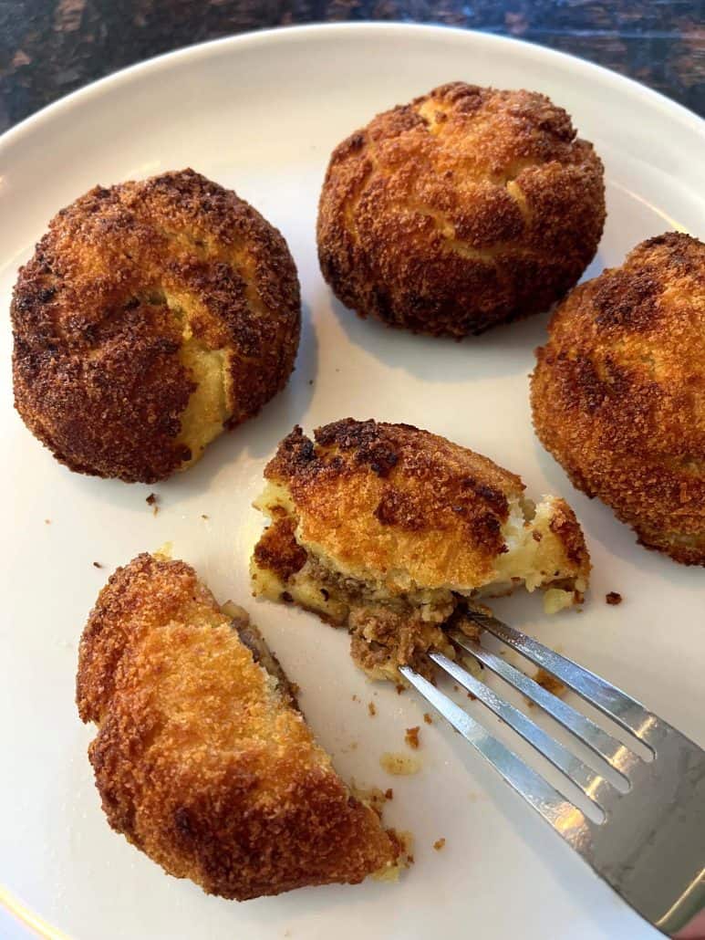Fork cutting into a Trader Joe’s Papas Rellenas to reveal the seasoned beef filling inside.