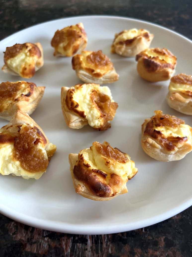 Side angle of golden brown Trader Joe’s Pastry Bites on a white plate, showing their crispy edges and cheesy filling after air frying.