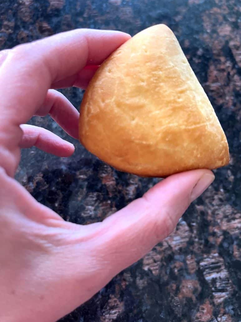 Close-up of a hand holding a golden, crispy Trader Joe’s Panzerotti Pizza Bite.