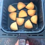 Golden brown Trader Joe’s Panzerotti Pizza Bites cooking in a single layer inside an air fryer basket, perfectly crisped and ready after 10 minutes.