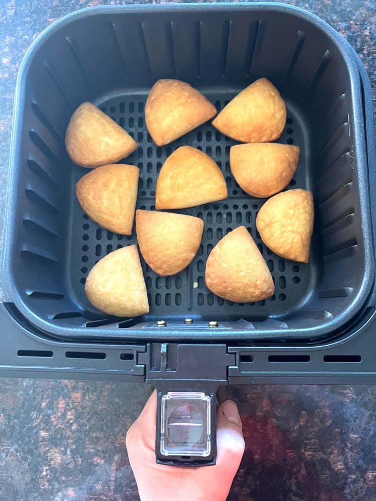Golden brown Trader Joe’s Panzerotti Pizza Bites cooking in a single layer inside an air fryer basket, perfectly crisped and ready after 10 minutes.