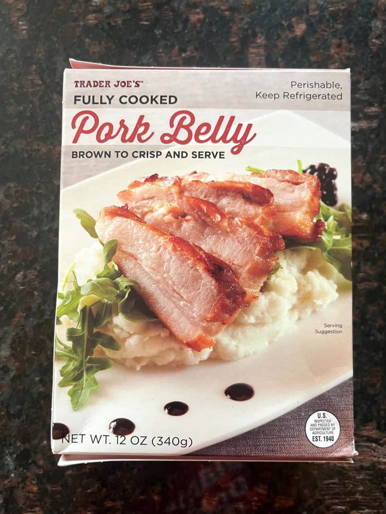 Package of Trader Joe’s Fully Cooked Pork Belly on a dark countertop, used in the easy air fryer recipe.