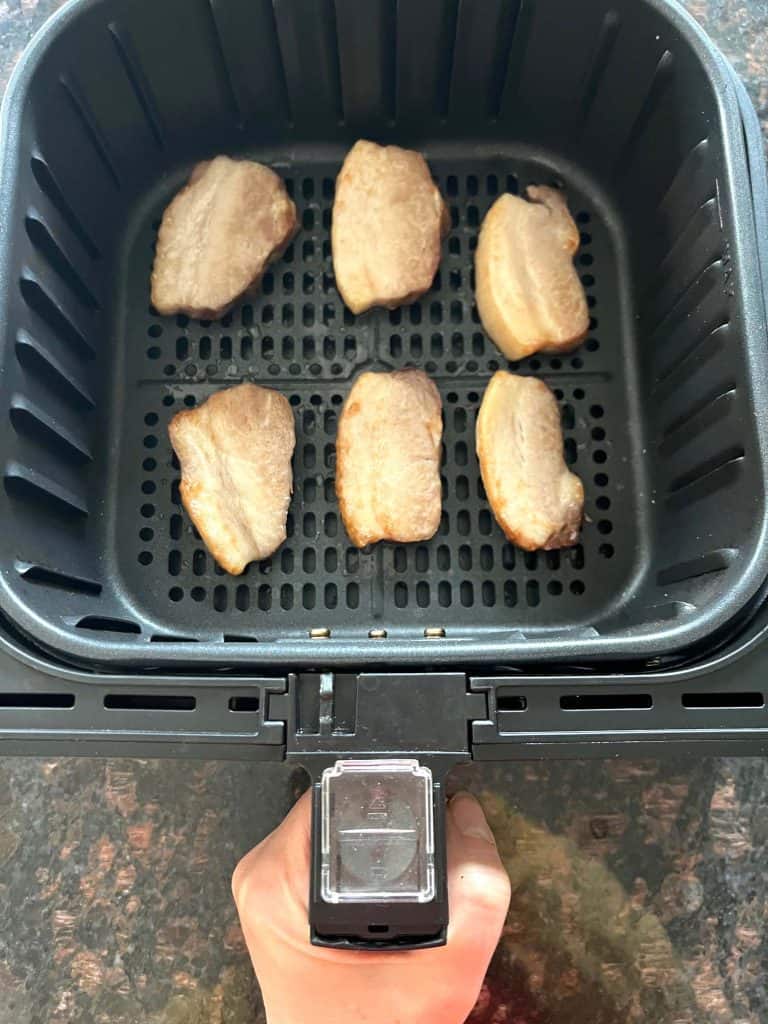 Air fryer basket with six Trader Joe’s pork belly slices cooking in a single layer—perfectly arranged for even crisping during the 9-minute air fryer recipe.