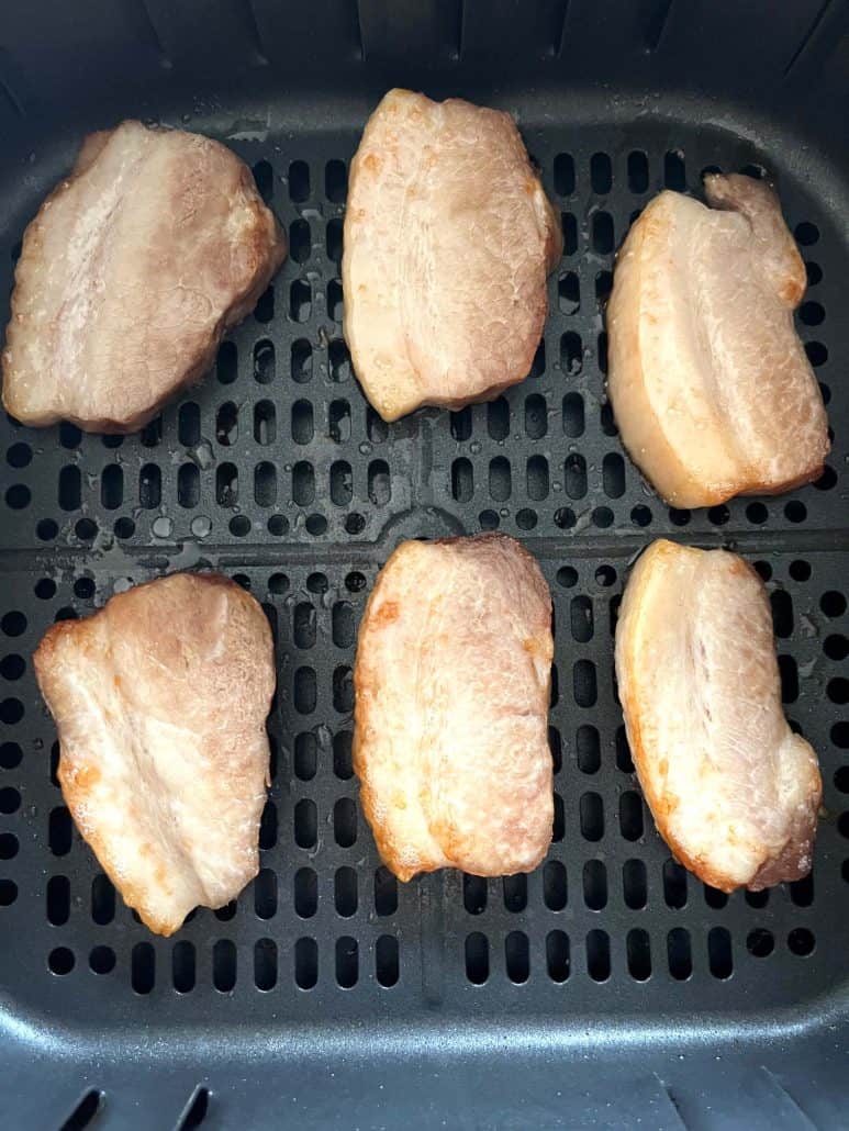 Six slices of perfectly browned Trader Joe’s pork belly placed in the air fryer basket.