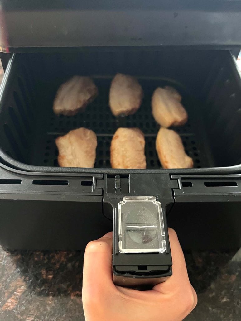 Sliced Trader Joe’s pork belly placed in an air fryer basket, ready to cook.