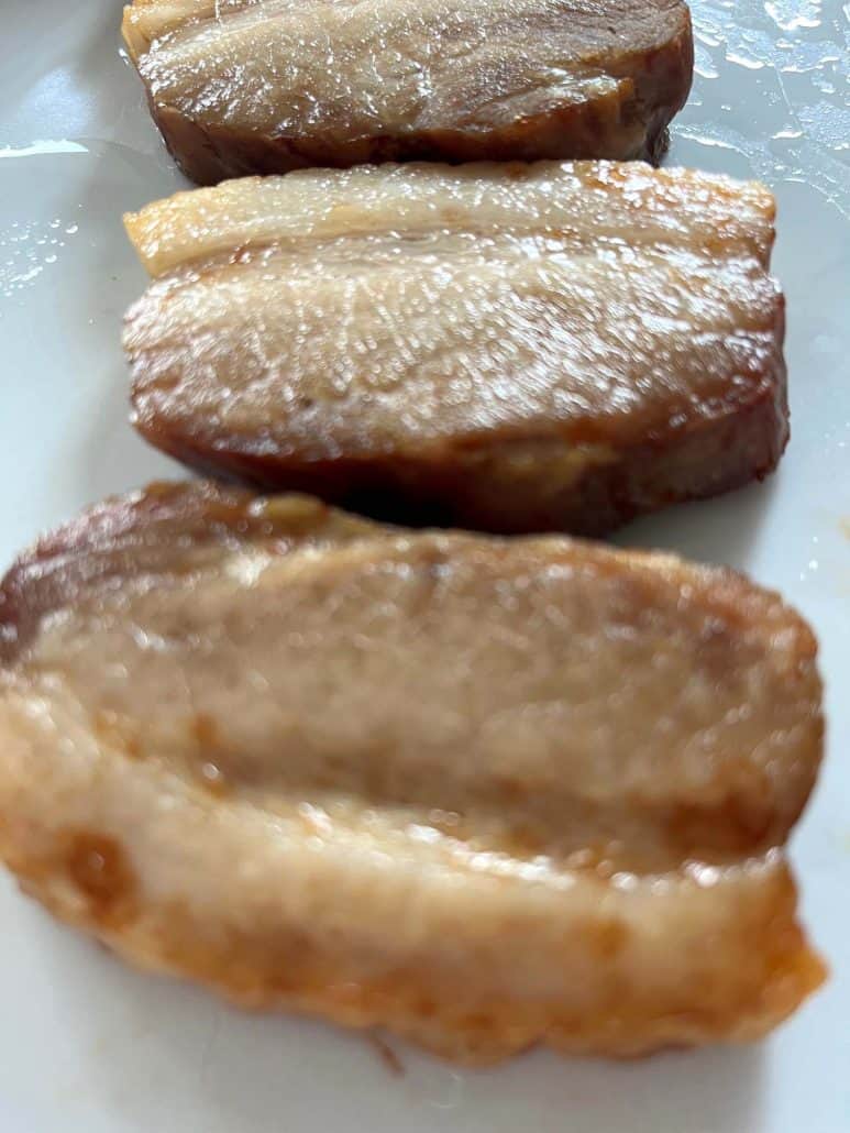 Close-up of crispy air-fried Trader Joe’s pork belly slices on a white plate, perfectly golden.