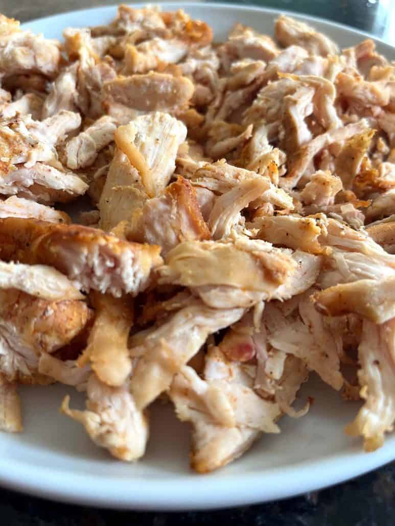 Close-up of crispy, golden pulled chicken on a white plate, air-fried to perfection.