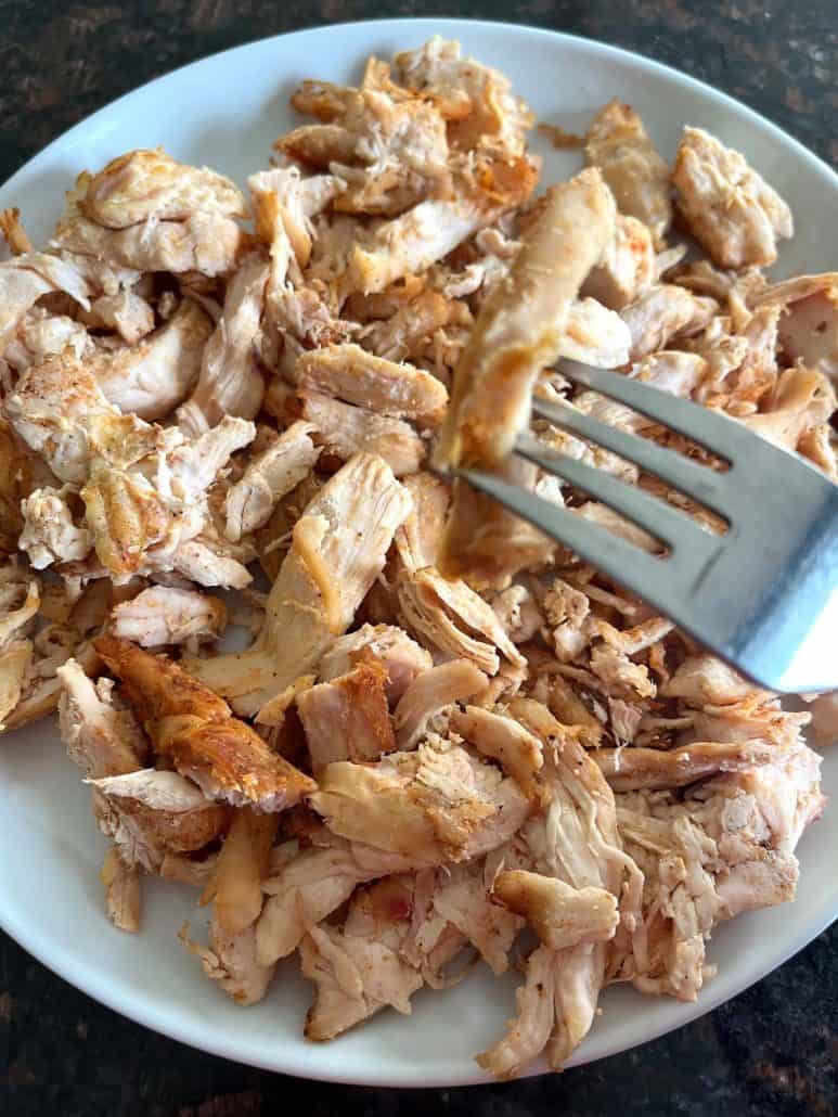 Close-up of air-fried Trader Joe’s pulled chicken on a plate with a fork, ready to serve.