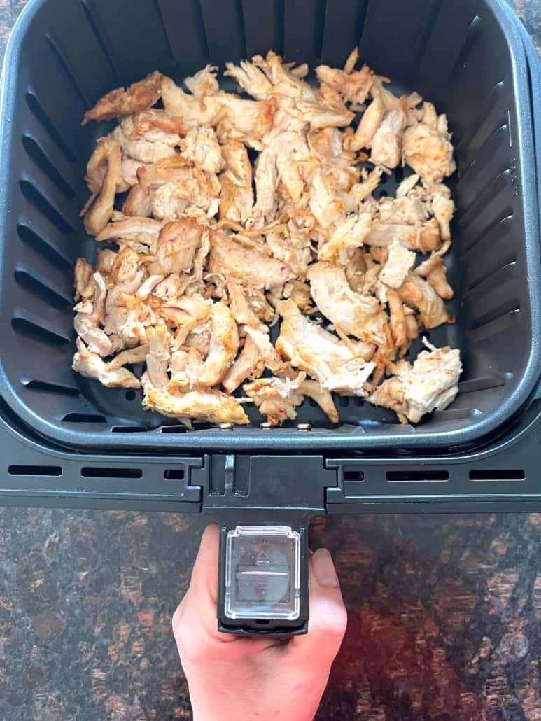 Trader Joe’s pulled chicken spread in an air fryer basket, ready to be cook.