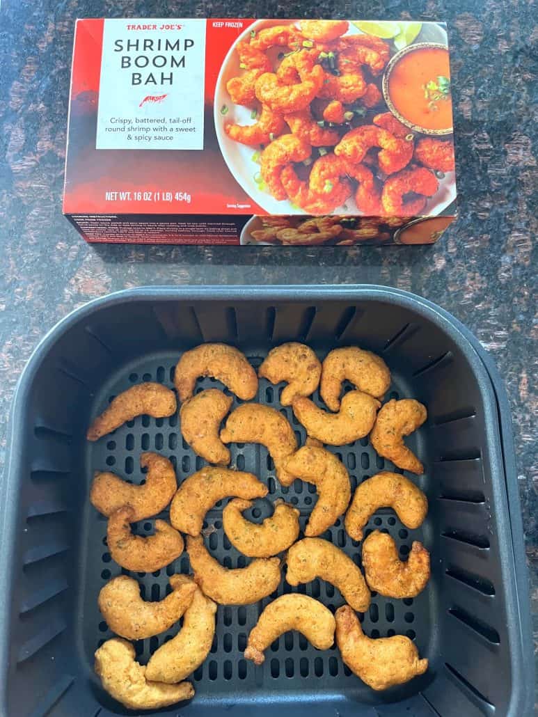 Cooked Trader Joe’s Shrimp Boom Bah in an air fryer basket with the product box nearby.