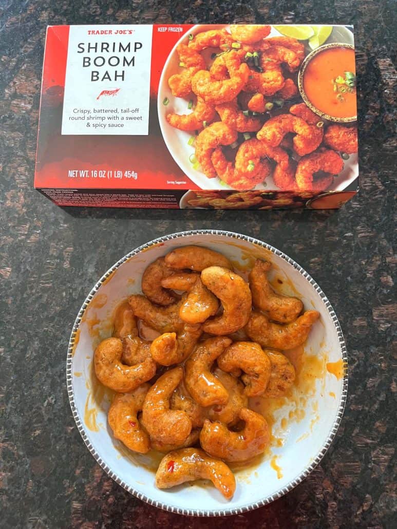 Bowl of sauced Trader Joe’s Shrimp Boom Bah next to the product box—crispy air fryer shrimp tossed in sweet and spicy sauce, ready to serve.