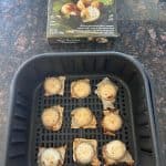 Air fryer basket with frozen Trader Joe’s Thai Coconut Pancakes (Kanom Krok) arranged in a single layer, with the product box shown above.
