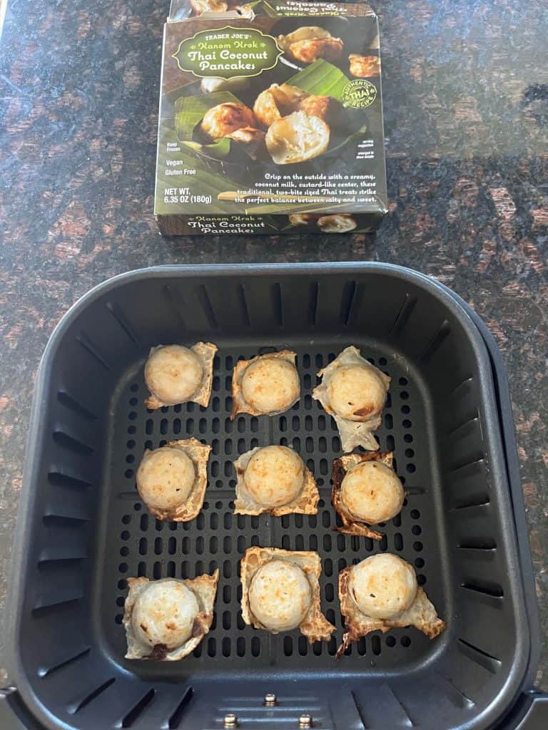 Air fryer basket with frozen Trader Joe’s Thai Coconut Pancakes (Kanom Krok) arranged in a single layer, with the product box shown above.