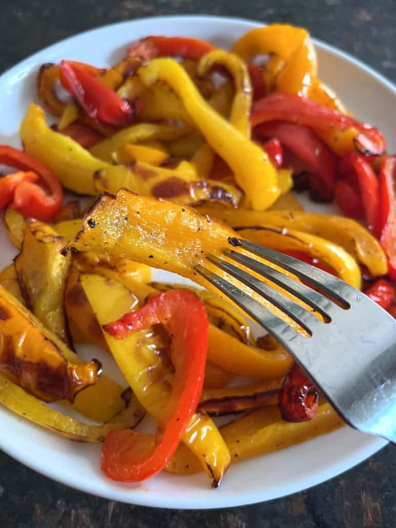 Fork picking up a slice of roasted bell pepper from a plate of tri-color peppers—freshly cooked from the Air Fryer.