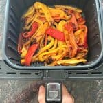 Colorful red, yellow, and orange bell pepper strips freshly roasted in an air fryer basket—perfectly cooked and ready to serve.