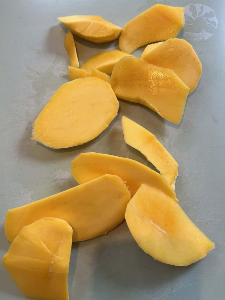 Uniformly sliced pieces of Philippine Carabao (Manila) mango arranged on a cutting board, ready to serve.