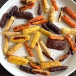 Plate of oven roasted tri-color baby carrots with golden brown edges, showcasing the finished dish from the Oven Roasted Tri-Color Carrots Recipe.
