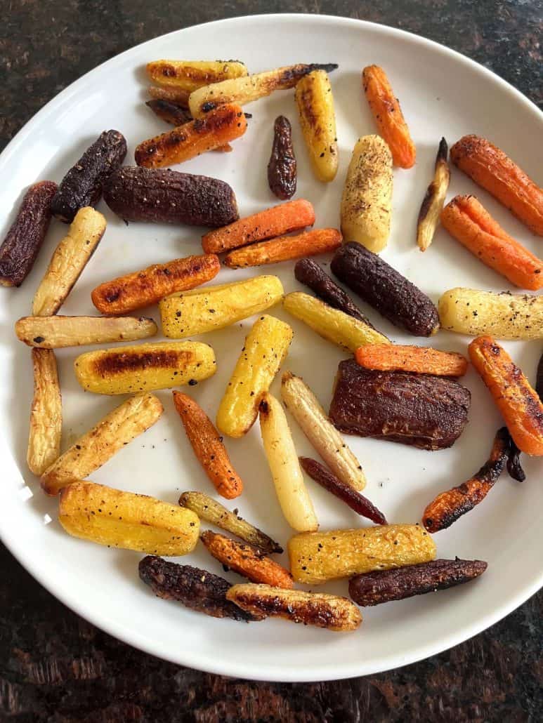 Plate of oven roasted tri-color baby carrots with golden brown edges, showcasing the finished dish from the Oven Roasted Tri-Color Carrots Recipe.