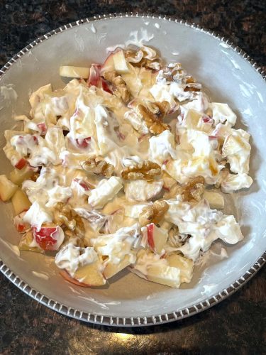 Bowl of apple raisin salad mixed with Greek yogurt, showcasing the creamy texture and fresh fruit ingredients from the healthy recipe.