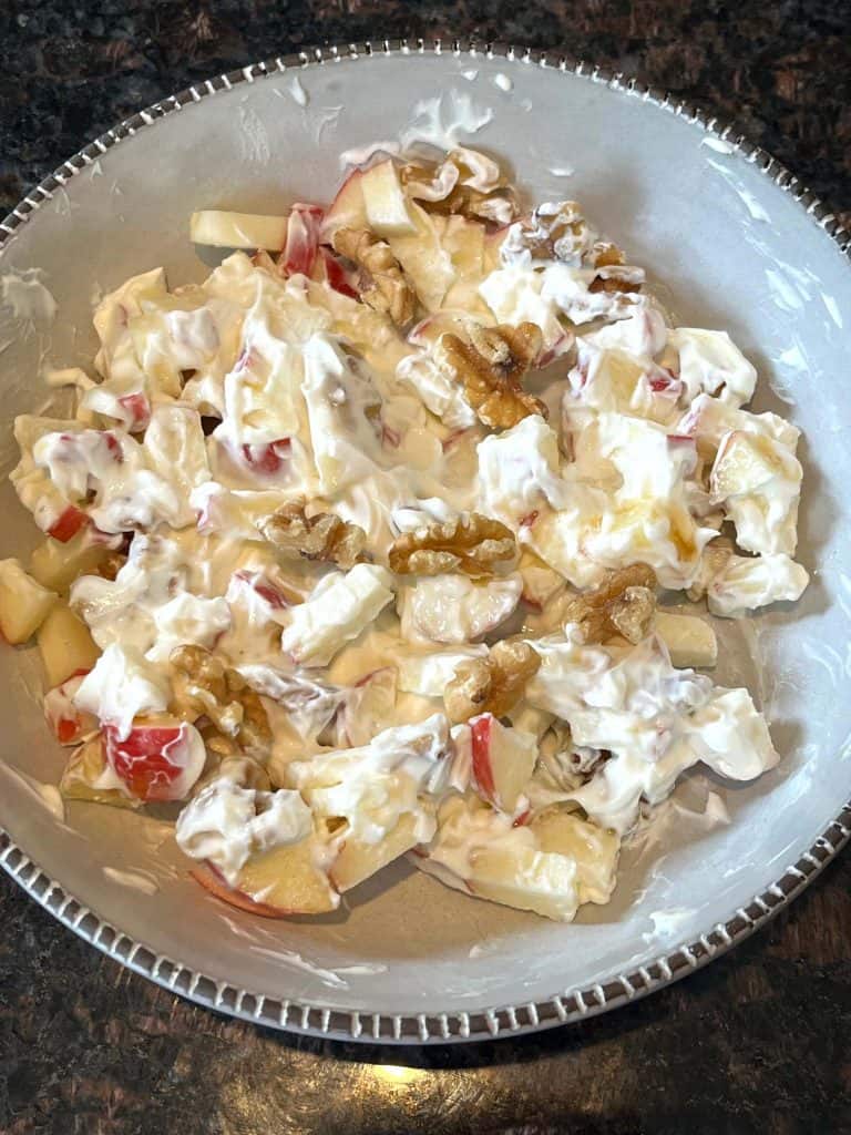 Bowl of apple raisin salad mixed with Greek yogurt, showcasing the creamy texture and fresh fruit ingredients from the healthy recipe.