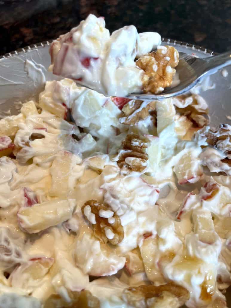 Spoon hovering over a Skyr bowl filled with chopped apples and walnuts, showing a close-up of the creamy, protein-rich breakfast.