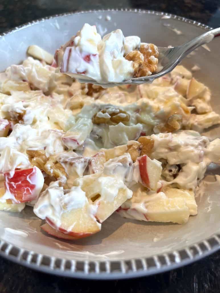 Close-up of a spoonful of Skyr, apple, and walnut mixture being lifted from the bowl, capturing the creamy texture and fresh ingredients.