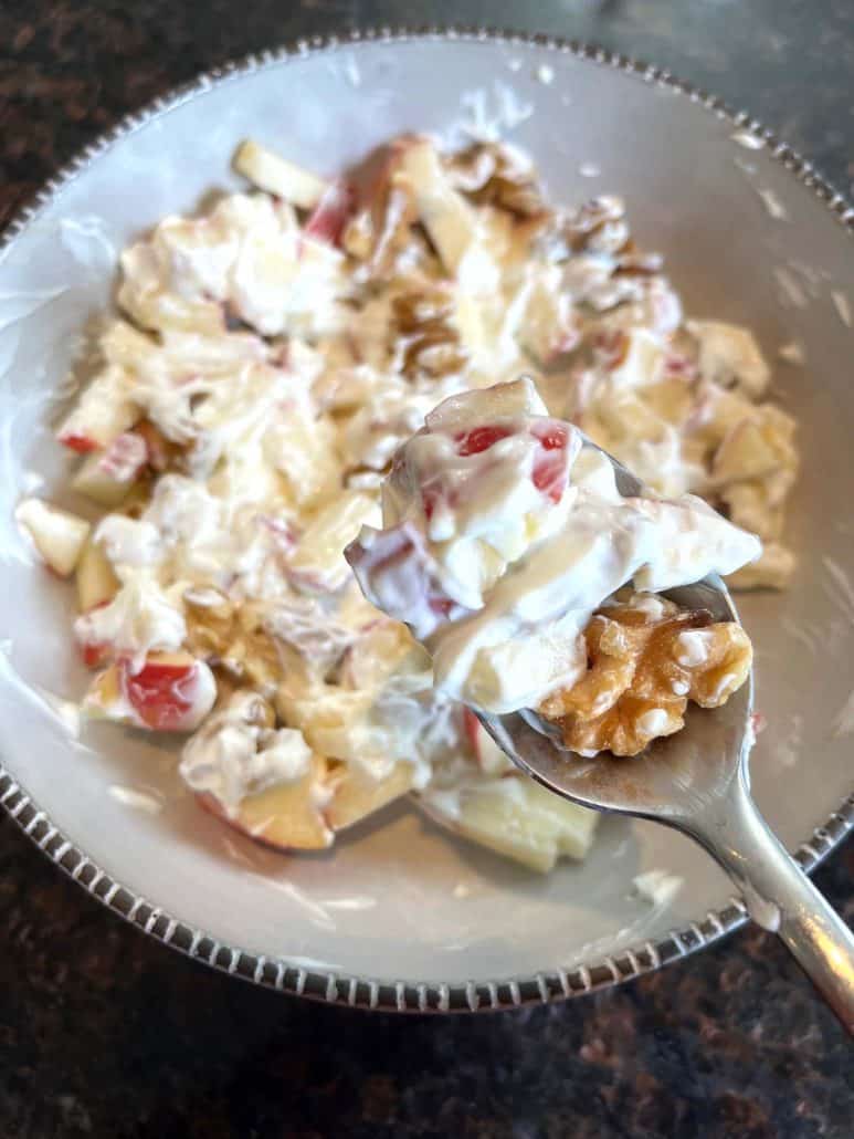 Spoonful of Skyr bowl with apples and walnuts lifted from the dish, showing the creamy, crunchy goodness of this healthy, no-cook breakfast recipe.