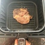 Delmonico steak cooking in the air fryer basket, showing a perfect sear.