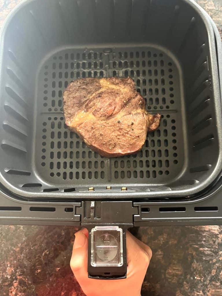 Delmonico steak cooking in the air fryer basket, showing a perfect sear.