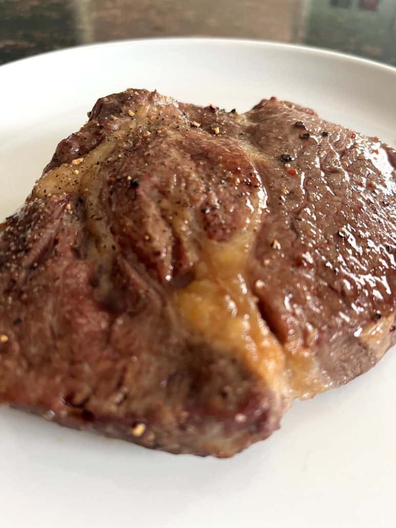 Juicy, golden-brown air fried Delmonico steak on a white plate, showing tender texture and caramelized surface.