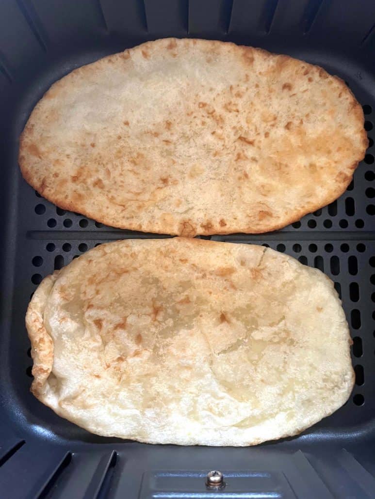 Top-down view of two air-fried bhatura in the basket—showing the golden, puffy texture.