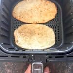 Two golden brown frozen bhatura breads cooking in an air fryer basket—perfectly puffed and ready in just 3 minutes using this easy air fryer method.