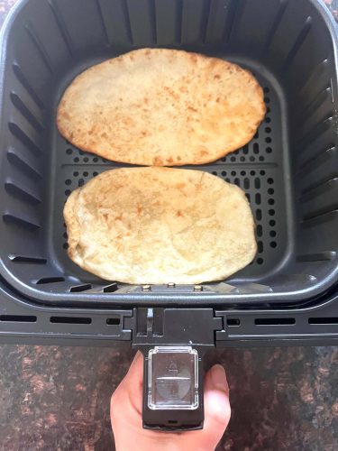 Air Fryer Bhatura - From Frozen To Warm, Soft & Delicious! Two golden brown frozen bhatura breads cooking in an air fryer basket—perfectly puffed and ready in just 3 minutes using this easy air fryer method.