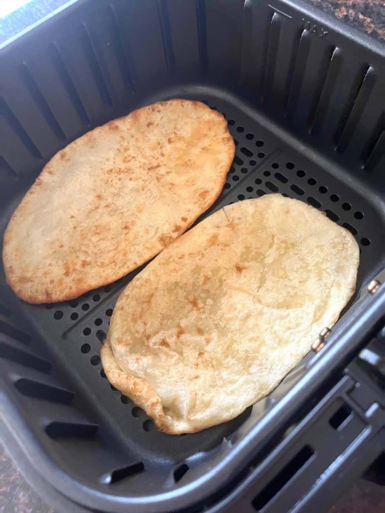 Two golden bhatura in an air fryer basket—crispy, puffed, and perfectly cooked.