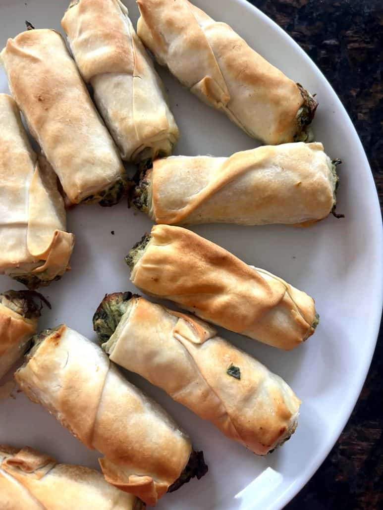 Golden brown borek bites arranged on a white plate, highlighting the flaky pastry and spinach filling.