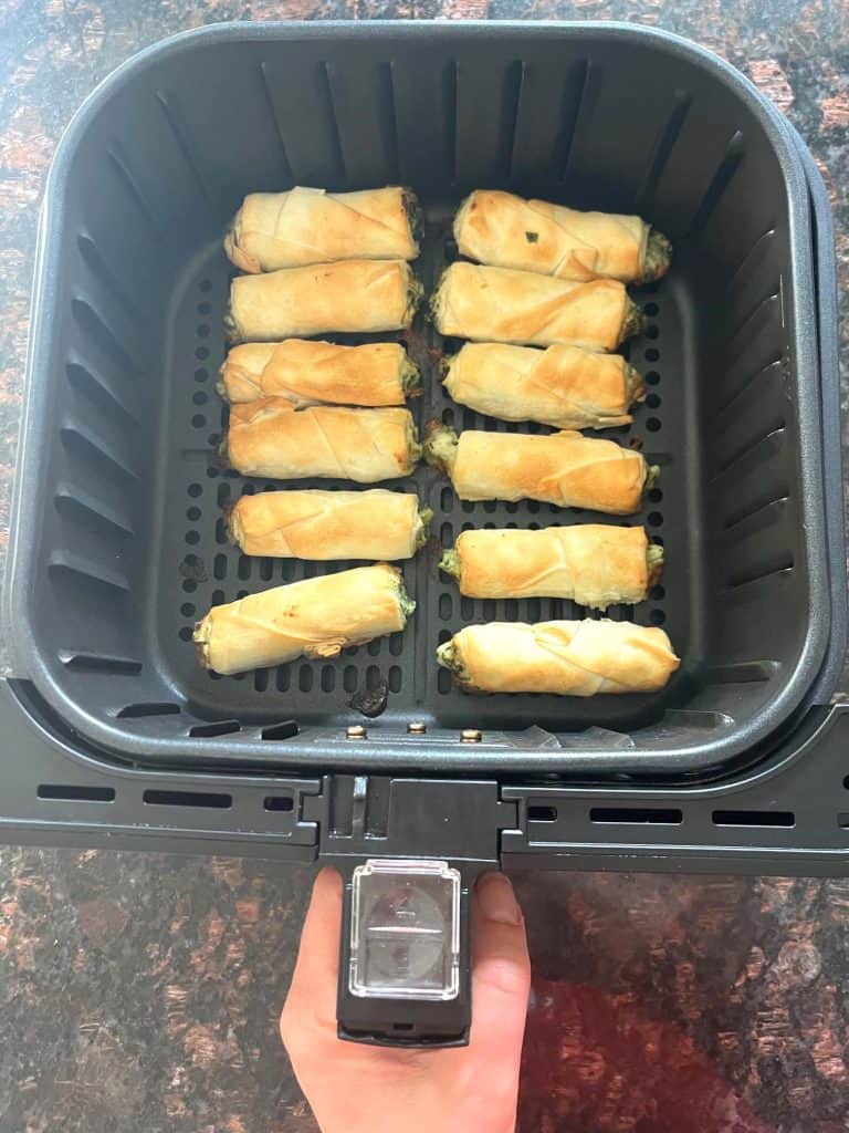 Crispy golden borek bites cooking in an air fryer basket—perfectly cooked.