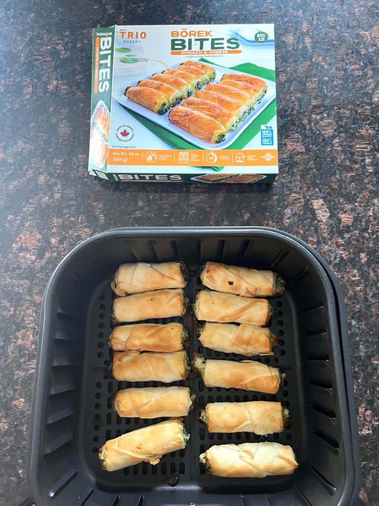 Cooked borek bites in the air fryer basket placed below the product packaging—highlighting the finished result.