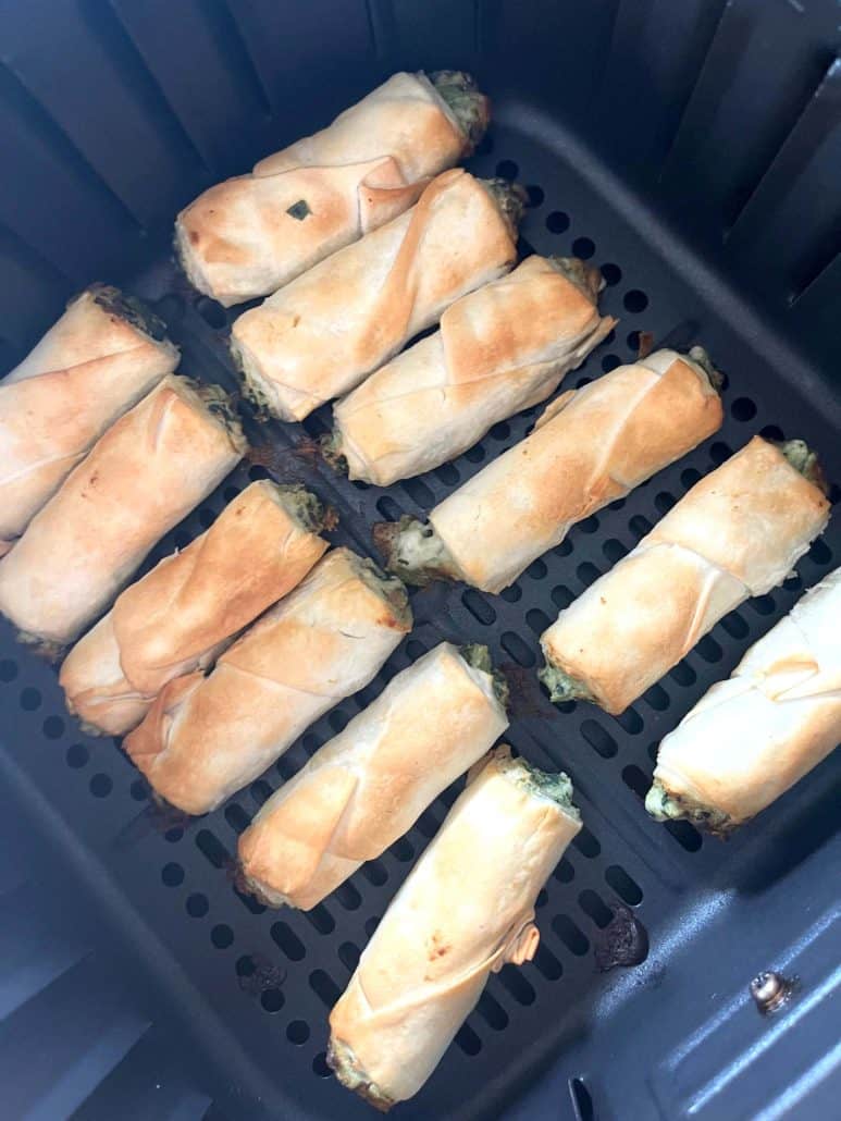 Angled view of crispy borek bites in the air fryer basket, showing their flaky texture and even browning.