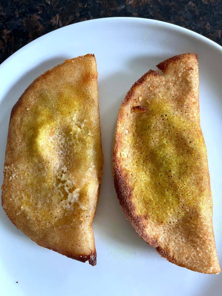 Two golden brown masala dosas served on a white plate—freshly cooked in the air fryer.
