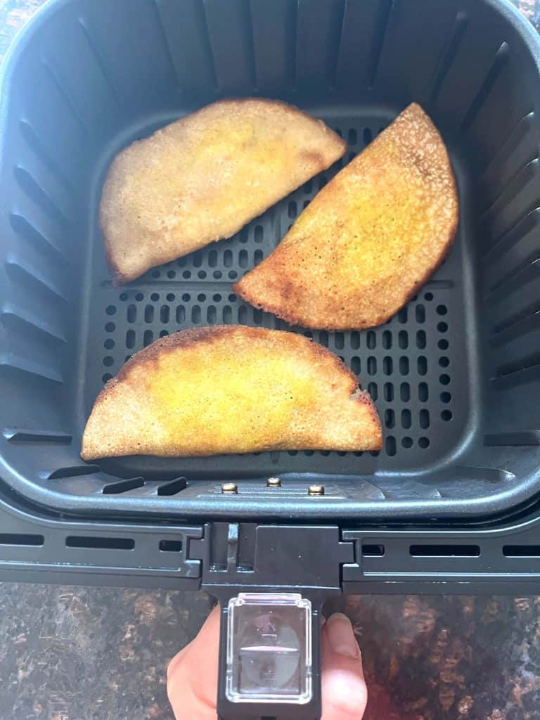 Three golden brown frozen masala dosas cooking in an air fryer basket—perfectly crisped using the no-preheat air fryer method.