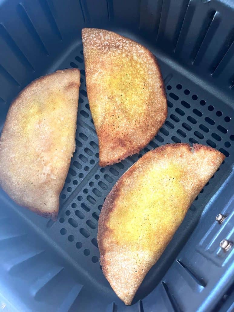 Three fully cooked frozen masala dosas inside an air fryer basket—crispy, golden, and ready to serve!
