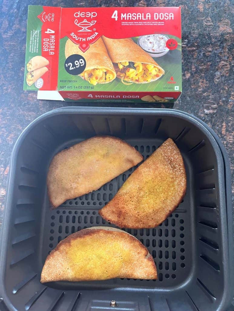 Cooked masala dosas in an air fryer basket placed next to the frozen dosa box—showing the before and after results of this easy air fryer recipe.