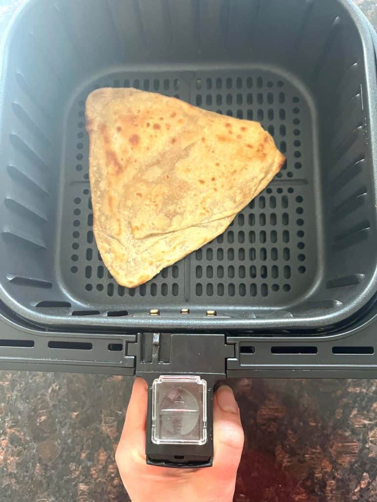 Frozen paratha placed in an air fryer basket, ready to be cooked at 400°F for 3 minutes.