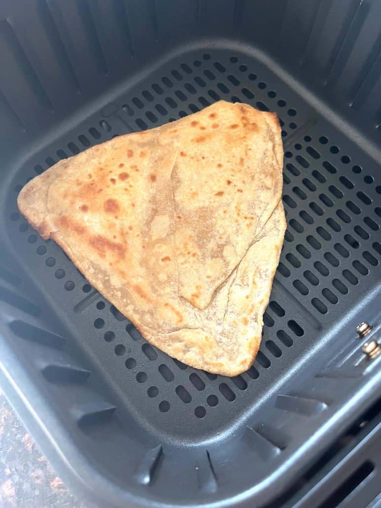Freshly air-fried paratha in the basket, golden brown and ready to serve.