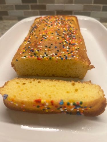 Loaf of cake with colorful sprinkles, sliced to reveal a soft, moist interior. This small cake made with 1 cup of cake mix is a simple, fun treat perfect for celebrations or a quick dessert.